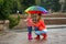 Happy mother and daughter with bright umbrella under rain