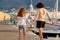 Happy mother and daughter child walking together holding hands along seafront