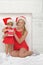 Happy mother and daughter dressed as Santa with gift, snow