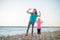 Happy mother and daughter in fitness gear on beach flexing arms