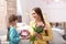 Happy mother and daughter with flower bouquet and gift at home.