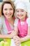 Happy mother and daughter in pink apron.