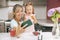 Happy mother and daughter sit at the table in the kitchen and watch educational videos on the phone. Mom records a video