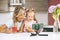 Happy mother and daughter sit at the table in the kitchen and watch educational videos on the phone. Mom records a video for her