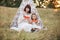 Happy mother and daughter, sitting in front of boho wigwam teepee with watermelon pieces