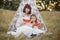 Happy mother and daughter, sitting in front of boho wigwam teepee with watermelon pieces