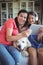 Happy mother and daughter sitting with pet dog and listening to music on headphones