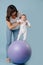 Happy mother doing exercises with her infant child baby on purple yoga ball