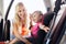 Happy mother fastening child with car seat belt