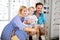 Happy mother and father choosing eyeglasses frame with their daughter in optical store