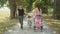 Happy mother and father hold their toddler girl`s hands while going for a fun walk in the sunny promenade.