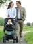 Happy mother and father smiling and pushing baby pram with child