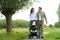 Happy mother and father walking with baby in pram