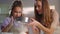 Happy mother helping daughter to sift flour with sifter on kitchen