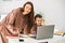 Happy mother helps her little son with online homework on laptop. Distance education.