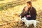 Happy mother and her daughter playing with dog in autumn park. Family, pet, domestic animal and lifestyle concept. Autumn time. Ha