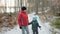 Happy mother and her daughter walking through a snowy forrest. Steadicam shot.