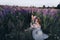 Happy mother and her little daughter in a field of lupins in summer. Mom holds her baby in arms