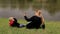 A happy mother with her son lies on the green grass on river bank in the spring.
