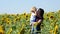 Happy mother and her son in a sunflower field at sunset. A young woman holds a baby in her arms.