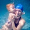 Happy mother holding baby in arms underwater.