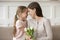 Happy mother holding white tulips touches foreheads with daughter