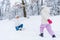 happy mother kneeling with open arms and little daughter walking in snow