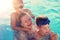 Happy mother laughing with sons in swimming pool