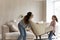 Happy mother with little daughter carrying armchair, decorating living room