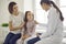 Happy mother and little daughter talking to friendly doctor during visit to the hospital