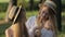 A happy mother and lucky daughter seating together and playing with apple in a city park on a picnic