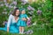 Happy mother mom with daughter enjoying time on a awesome place between lilac syringe bush.Young ladies with basket full of flower