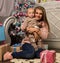 Happy mother with newborn son, sitting on a floor near a Christmas tree. Waiting for a holiday.