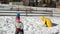 Happy Mother is Playing in Snowball Fight with Her Daughter Outdoors. Woman in Yellow Coat and Little Girl are Having