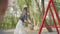 Happy mother pushing laughing two sons on swing in a park. Outdoor recreation.