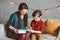 Happy mother reading book to child son at home, learning toddlers to read,