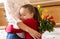 Happy Mother`s Day or Birthday Background. Adorable young girl hugging her mom after surprising her with bouquet of red roses.