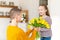 Happy Mother`s Day or Birthday Background. Adorable young girl surprising her mom with bouquet of tulips. Family celebration.