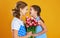 Happy mother`s day! child daughter gives mother a bouquet of flowers on color yellow background