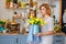 Happy Mother`s Day. The daughter congratulates her mother, and they hold a bouquet of yellow tulips in the kitchen
