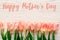 Happy mother`s day text sign on pink tulips on white rustic wood