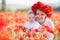 A happy mother with a small son in her arms on the endless field of red poppies on a sunny summer day