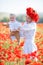 A happy mother with a small son in her arms on the endless field of red poppies on a sunny summer day