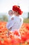 A happy mother with a small son in her arms on the endless field of red poppies on a sunny summer day