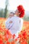 A happy mother with a small son in her arms on the endless field of red poppies on a sunny summer day