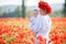 A happy mother with a small son in her arms on the endless field of red poppies on a sunny summer day