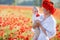 A happy mother with a small son in her arms on the endless field of red poppies on a sunny summer day