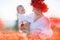 A happy mother with a small son in her arms on the endless field of red poppies on a sunny summer day