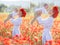 A happy mother with a small son in her arms on the endless field of red poppies on a sunny summer day