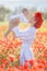 A happy mother with a small son in her arms on the endless field of red poppies on a sunny summer day